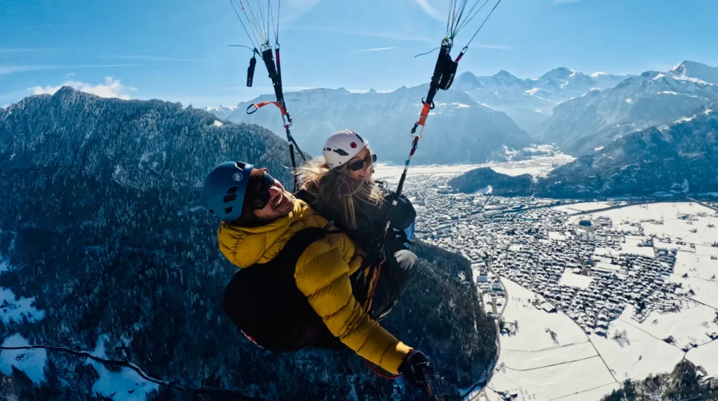 Paragliding Winter Interlaken mit verschneiten Bergen und Blick auf die Alpen